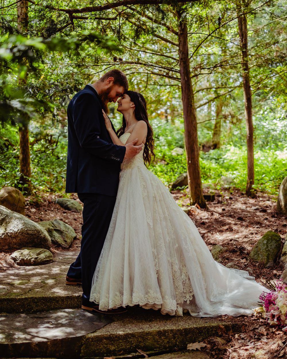 A tender moment between a couple on forest steps surrounded by green foliage.