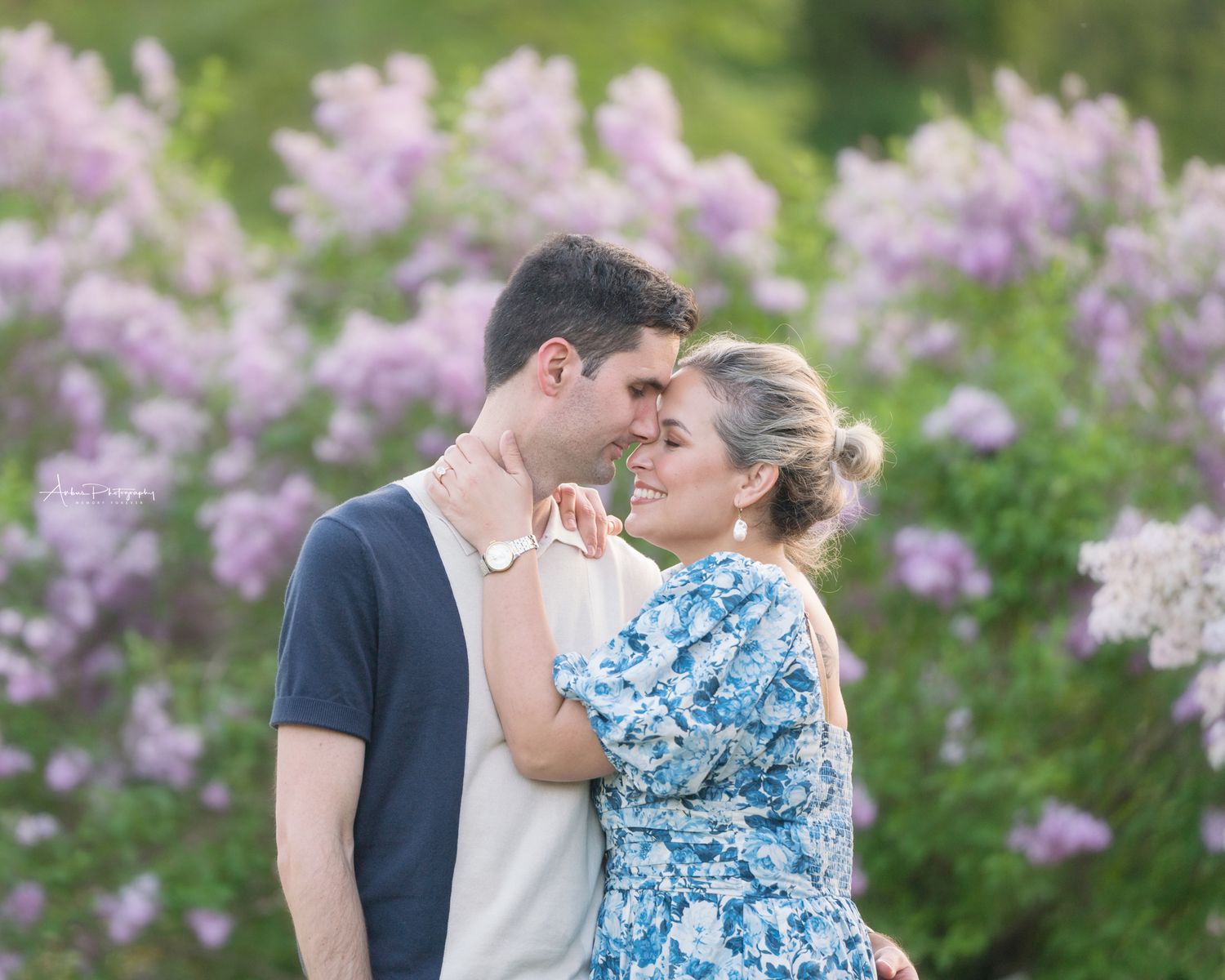 Romantic couple portrait among blooming lilac bushes in spring.
