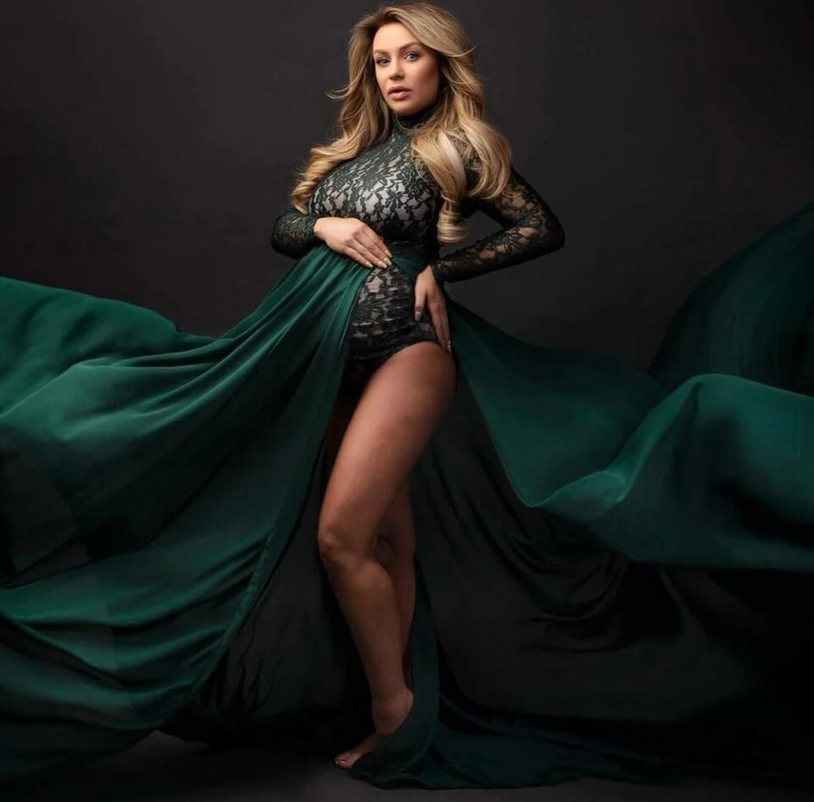 Dramatic maternity photos featuring flowing emerald green dress against black background.