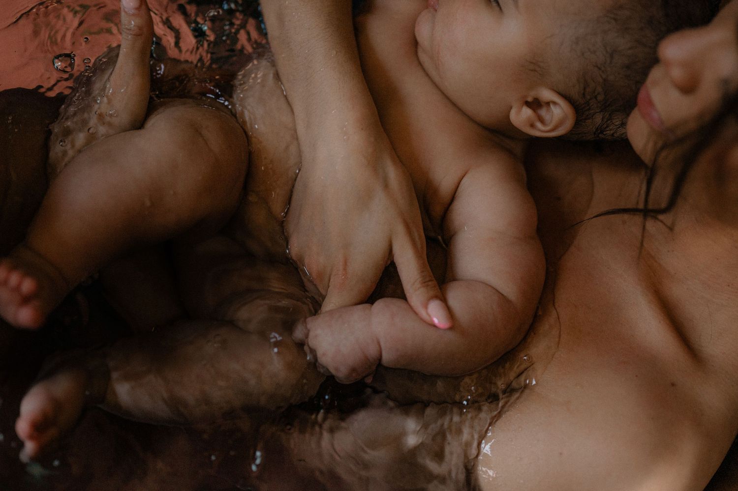 A close-up of a mother and her baby daughter laying in the bath during a photo session in Kent