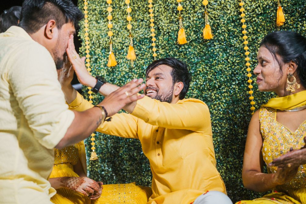 Festive celebration with people in yellow attire enjoying playful moments against green decor.