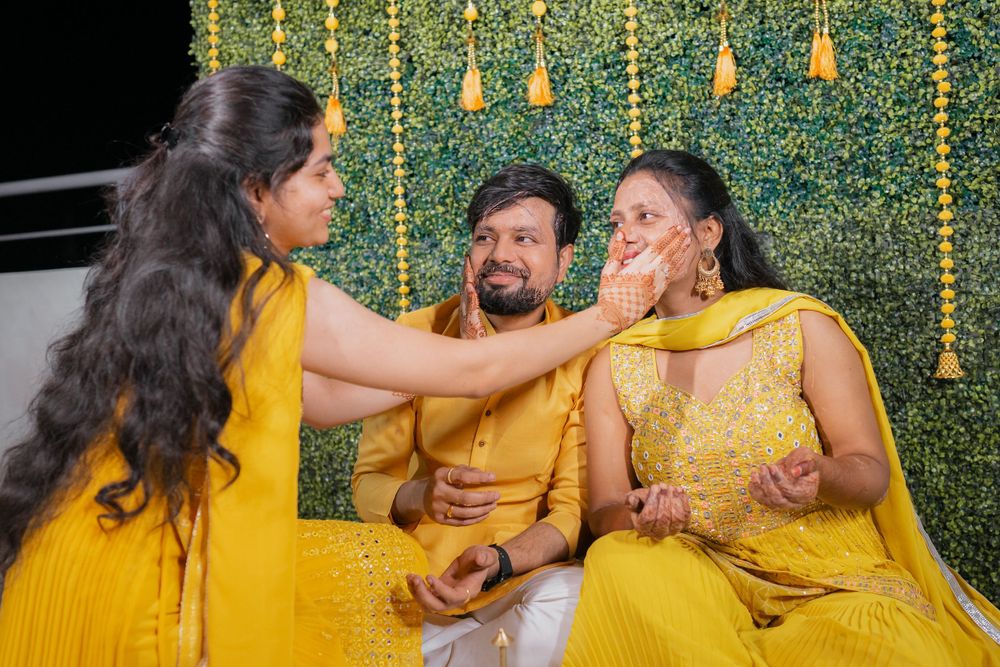 Traditional haldi ceremony with guests applying turmeric paste during Indian pre-wedding ritual.