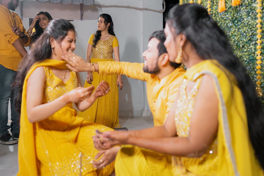 Group wearing yellow outfits participate in festive haldi ceremony traditions.