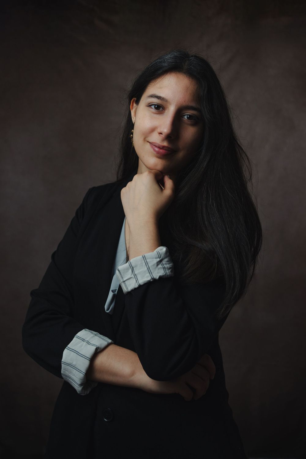 Professional portrait of person in black blazer with checked sleeve detail.