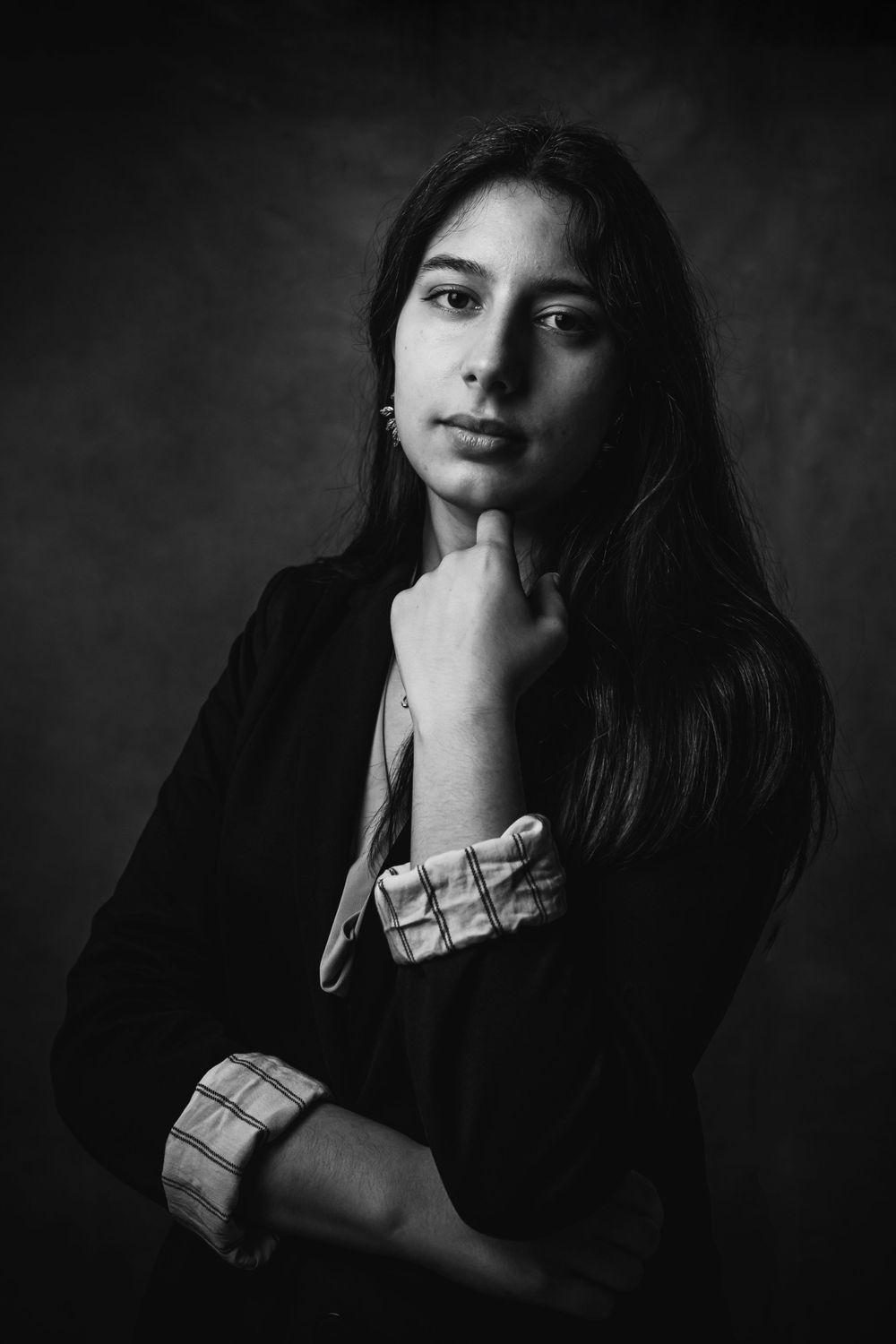 Black and white portrait of young professional in dark blazer with thoughtful pose.