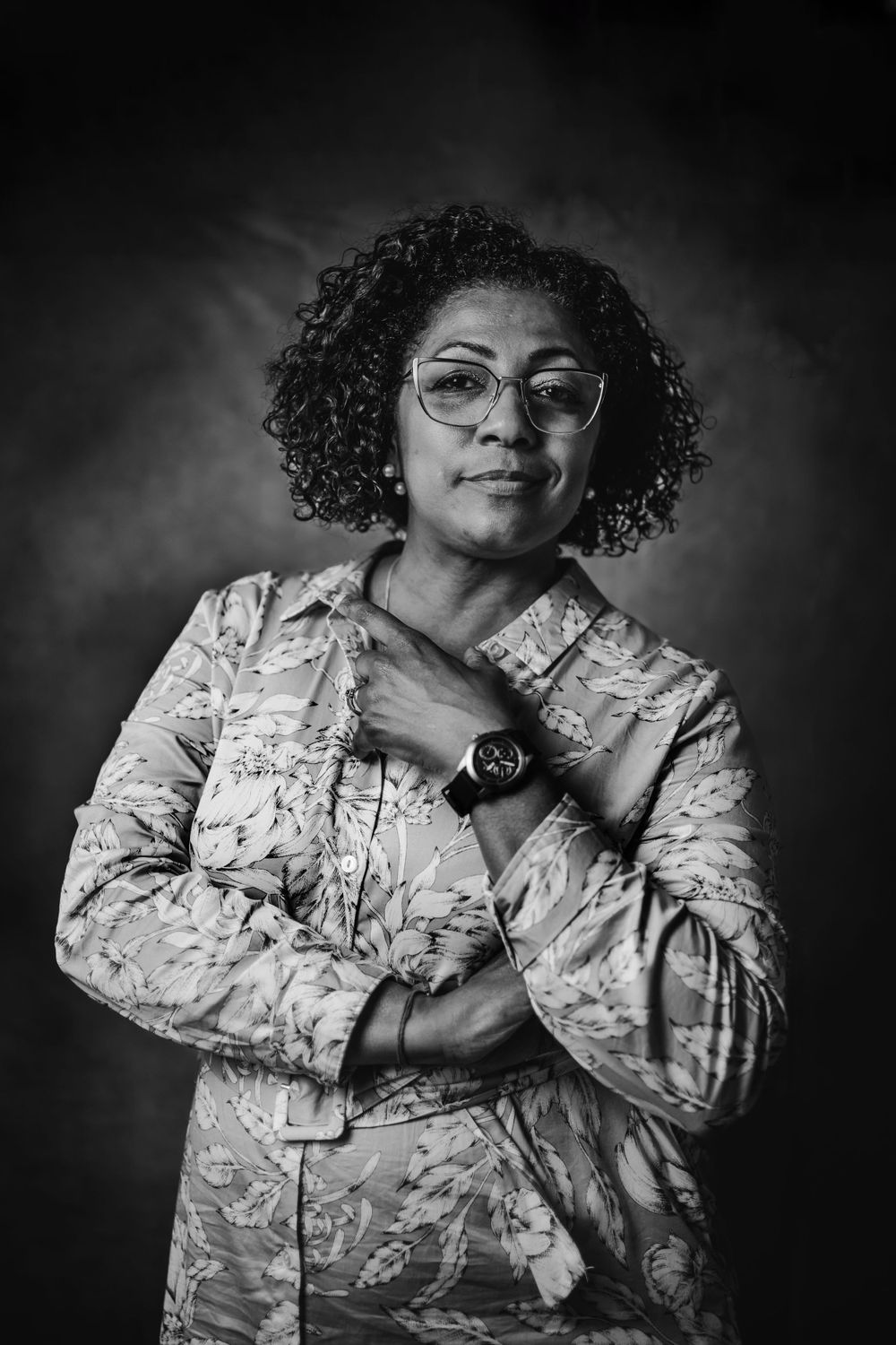 Professional studio portrait in black and white showing person in floral print uniform.