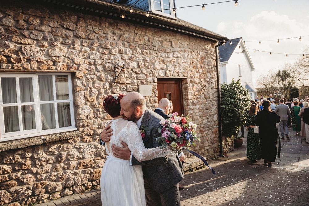 Stone wall venue decorated with string lights creates romantic atmosphere for wedding celebration.