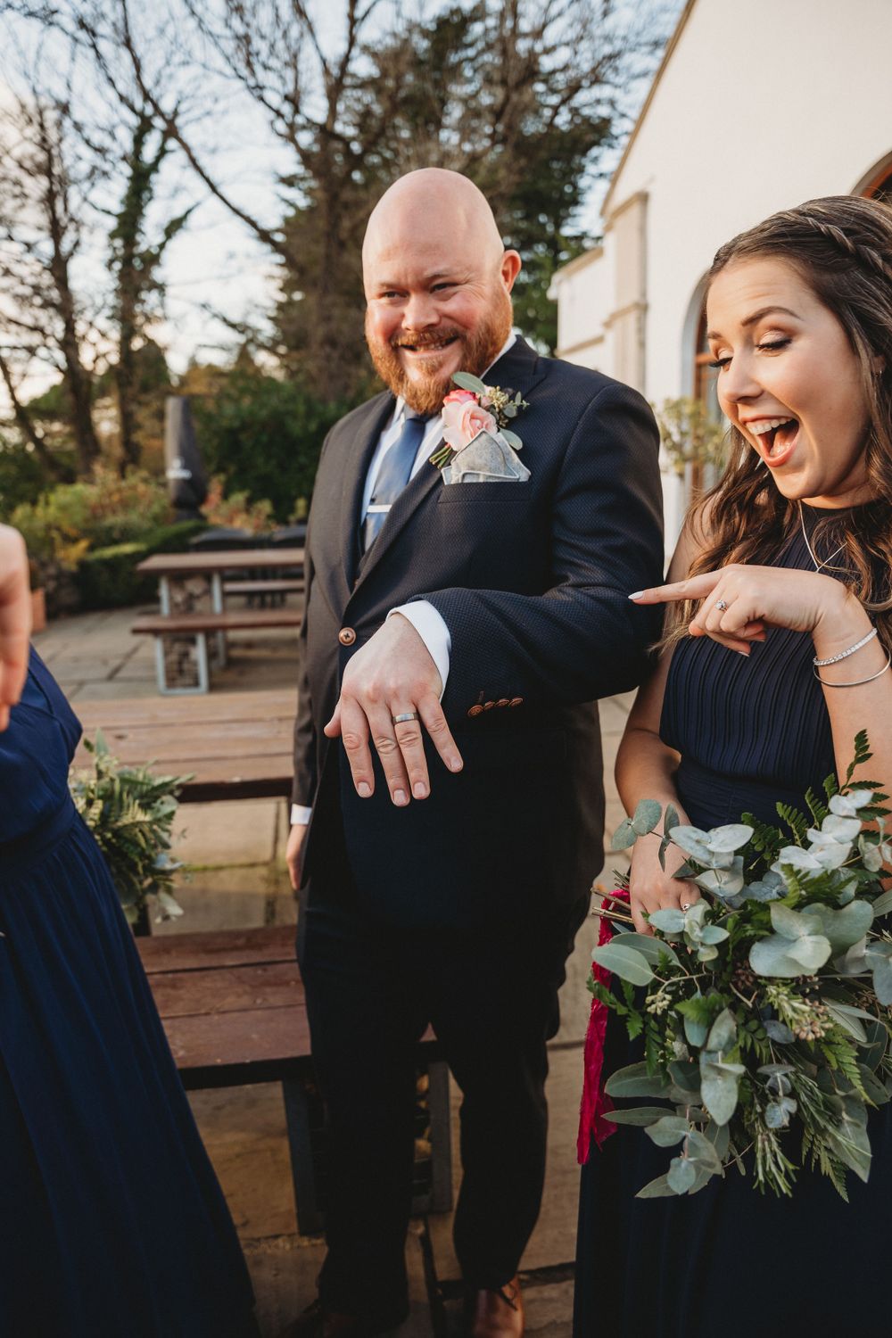 Wedding party members share candid laughing moments while holding bouquets.