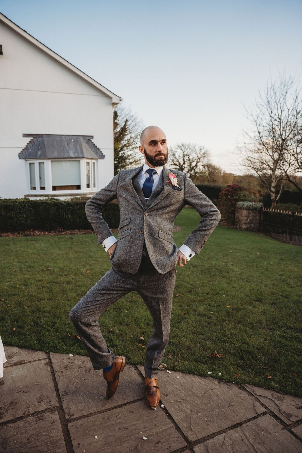 Person in grey suit strikes playful poses in sequence on garden path.