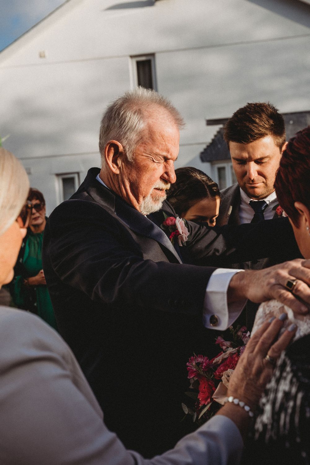 Emotional gathering of wedding guests sharing a touching moment outdoors.