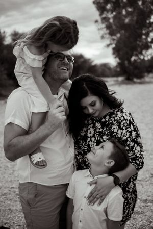 Black and white portrait of family sharing playful moment outdoors.