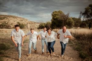 A group runs together down a dirt path in matching light-colored outfits against a scenic desert backdrop.