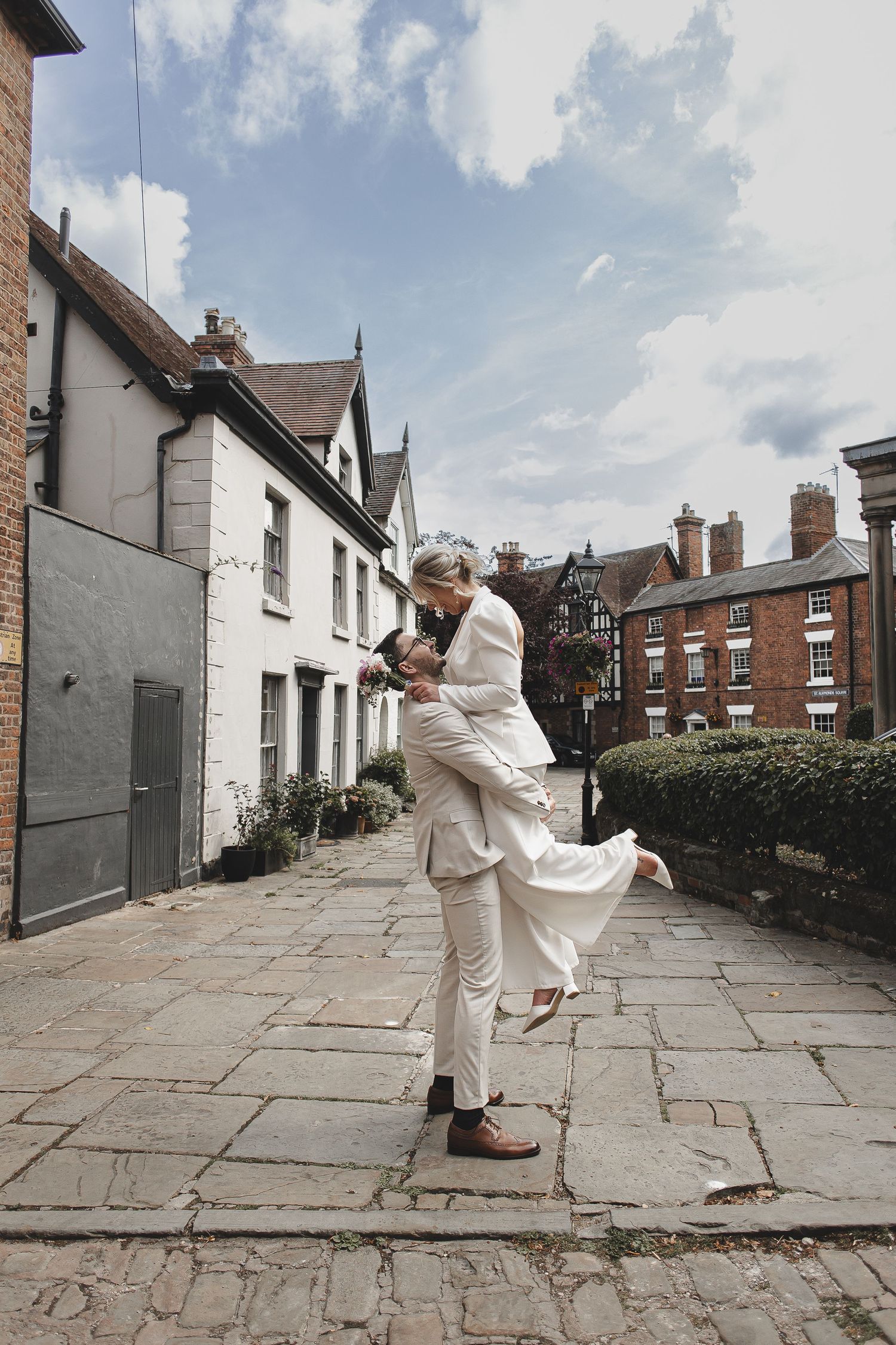A sequence of four photos showing someone in white clothing dancing on a stone pathway between residential buildings.