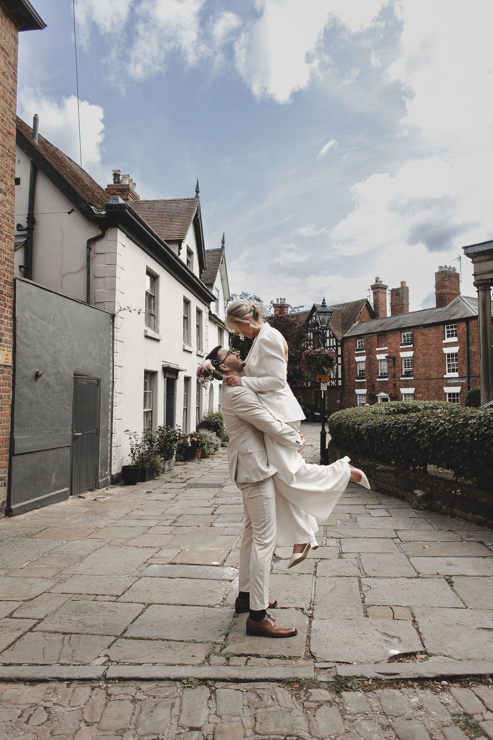A sequence of four photos showing someone in white clothing dancing on a stone pathway between residential buildings.