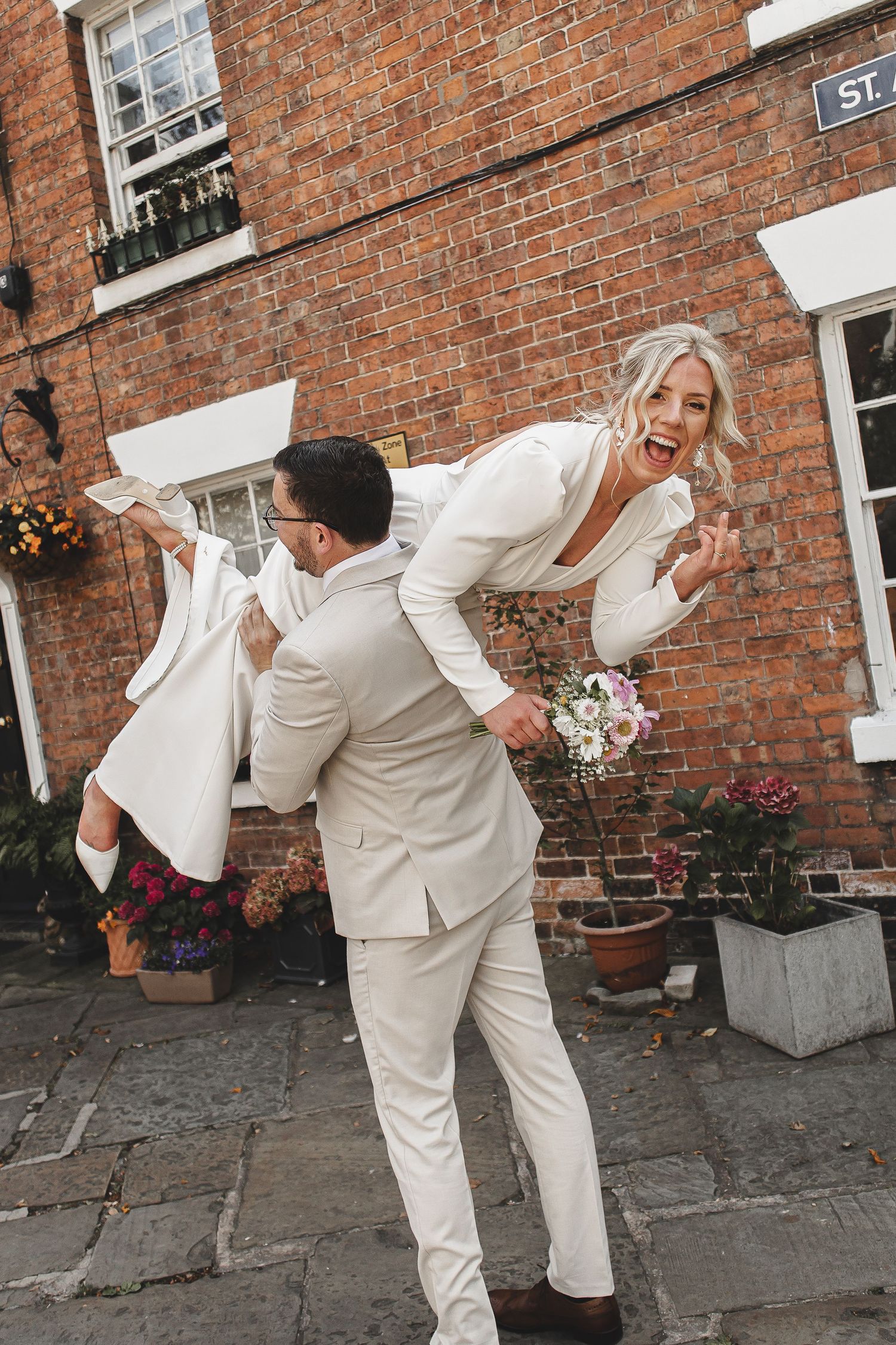 A sequence of four photos showing two people in white outfits dancing and posing playfully against a brick wall.