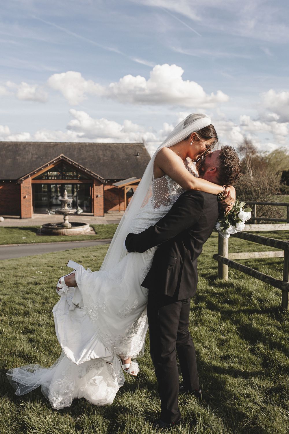 Romantic wedding couple dips and dances together in a grassy field on their special day.