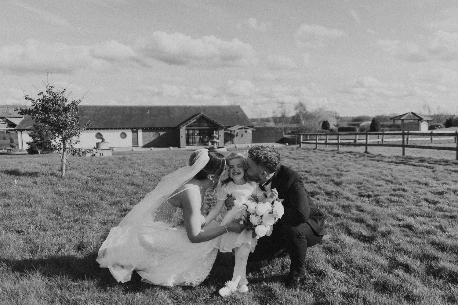 A series of black and white photos showing a couple in wedding attire lying in a grassy field during a photoshoot.