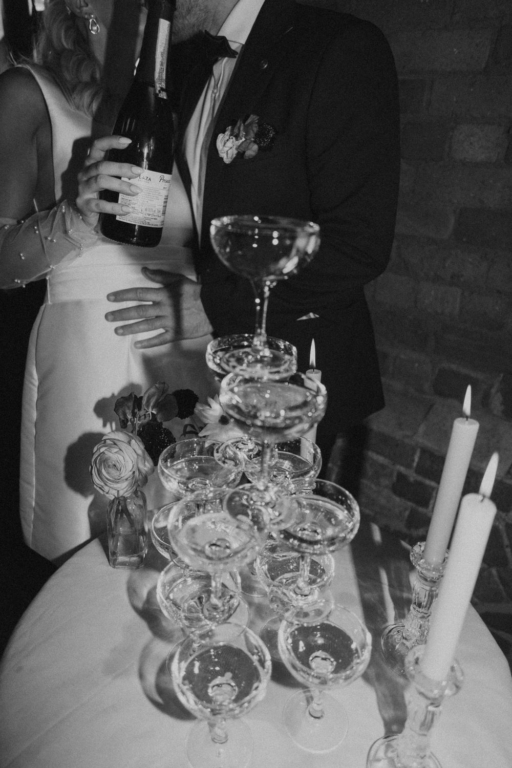 Black and white photograph of wine glasses and candles arranged on a table at an elegant event.