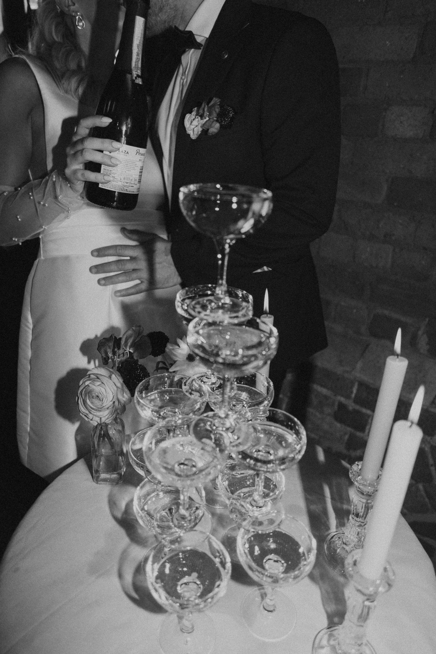 Black and white photograph of wine glasses and candles arranged on a table at an elegant event.