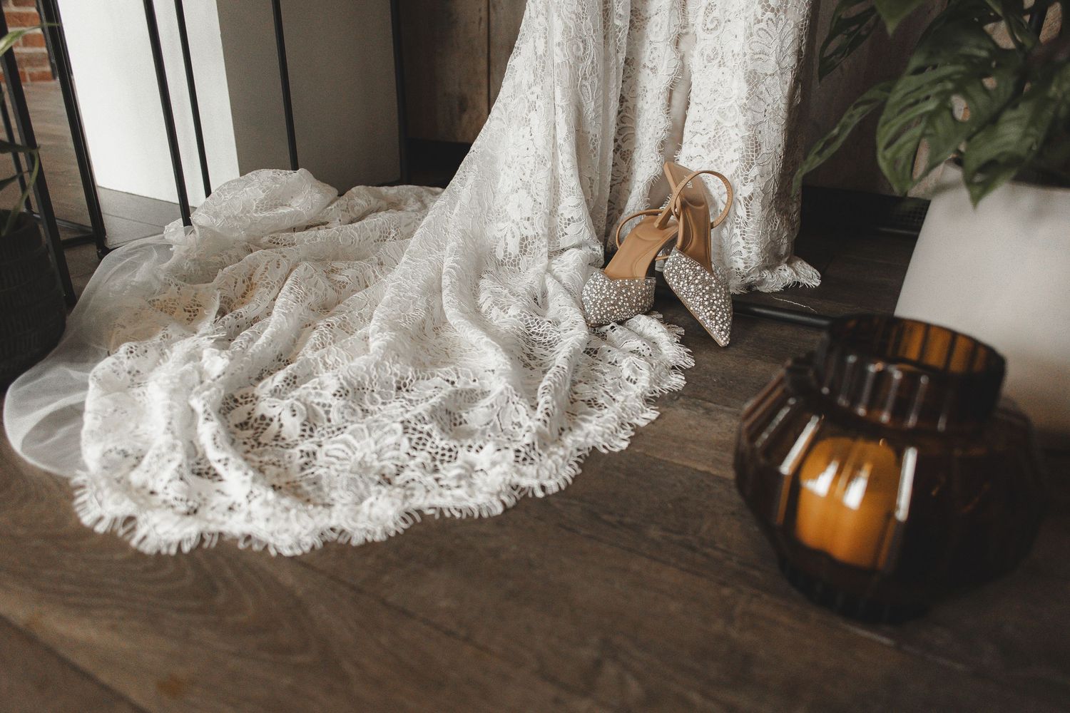A white lace wedding dress train elegantly draped across dark hardwood flooring with a pumpkin accent in the corner.