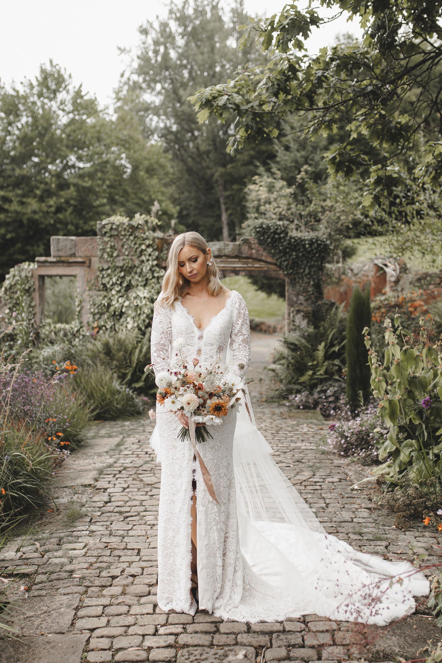 Ethereal bridal portraits in a romantic garden setting with stone pathways and lush florals.