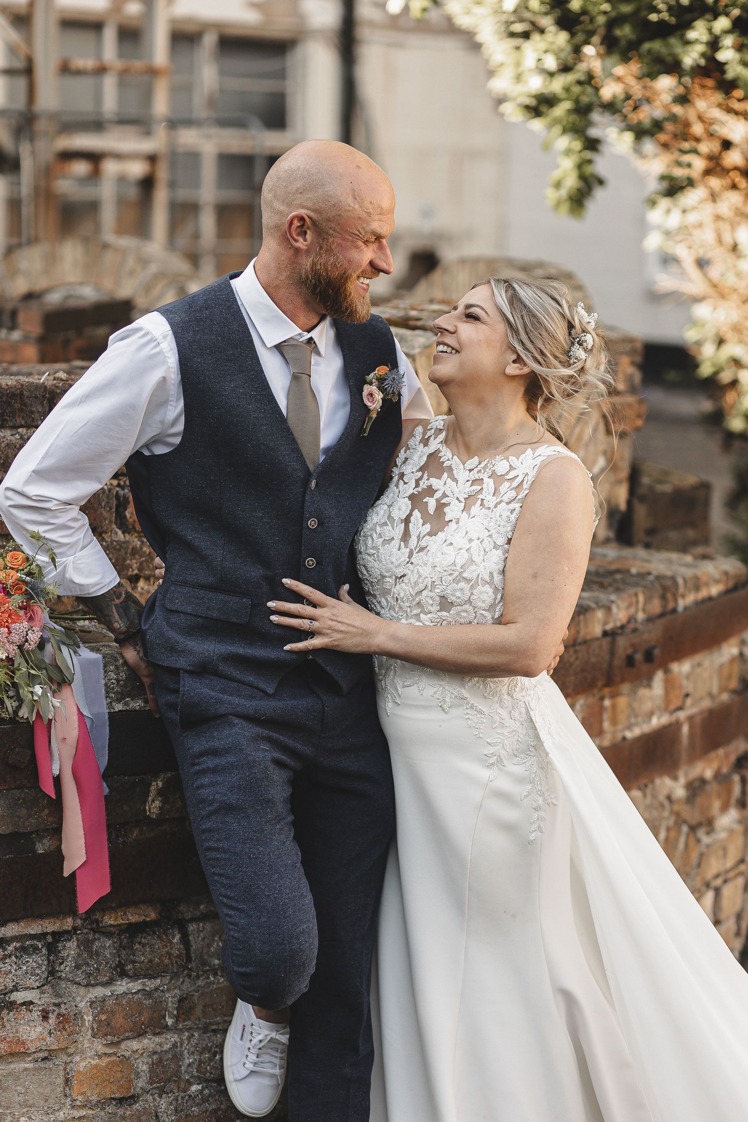 A romantic wedding couple shares intimate moments against a brick wall background in a series of candid photos.