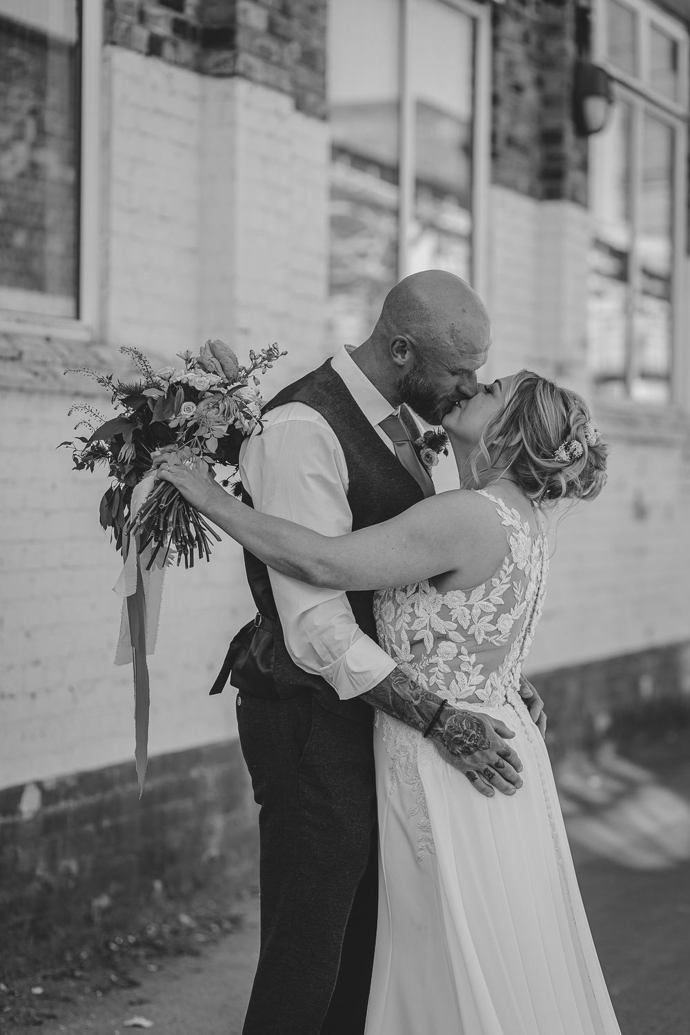 Black and white wedding photo series showing tender moments between a couple in formal attire embracing outdoors.