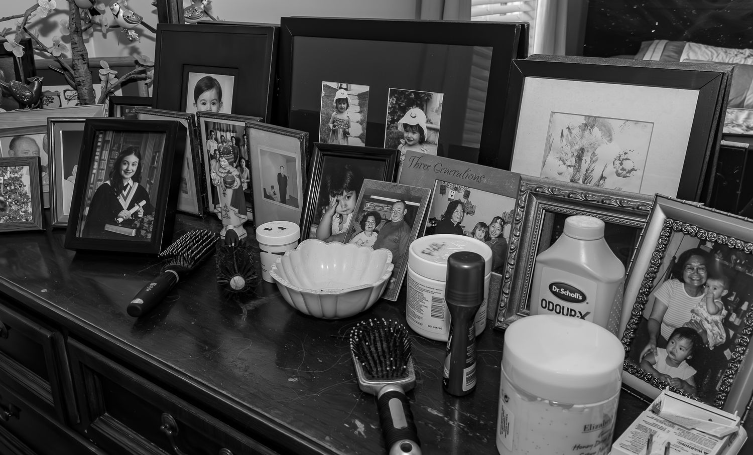 Black and white photograph of a dresser with pictures of many different generations