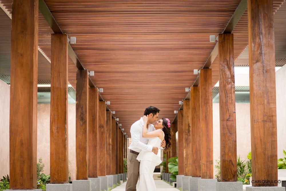 Couple sharing an intimate moment under a wooden covered walkway with pillars.
