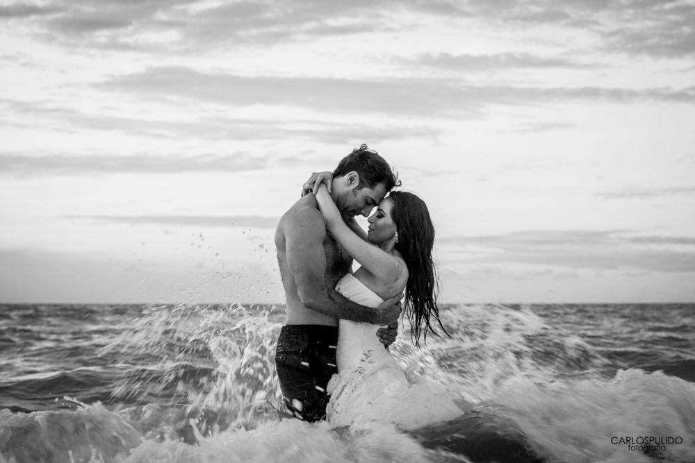 Black and white photo of couple embracing in ocean waves.