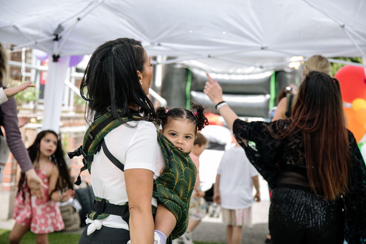People dancing and celebrating at an outdoor festival under white canopy tents.