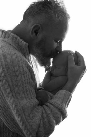 Father holding newborn baby in his hands whilst kissing him