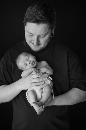 A tender black and white photo showing dad holding his baby boy.