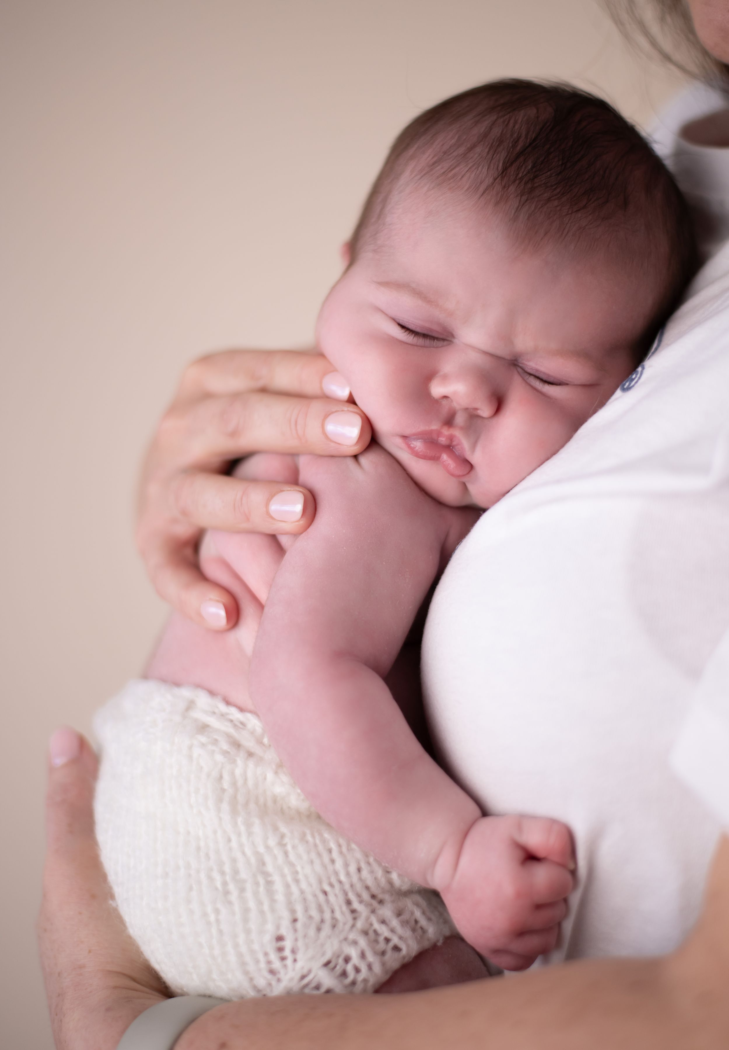 A sleeping baby in white knit fabric shorts peacefully on her mothers chest