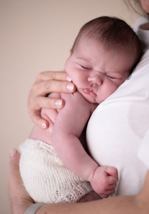 A sleeping baby in white knit fabric shorts peacefully on her mothers chest
