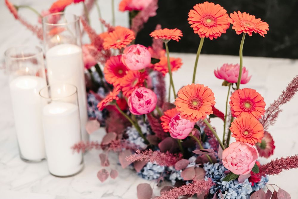 Pink and coral floral centerpieces with delicate blooms arranged in glass vases on an elegant table setting.
