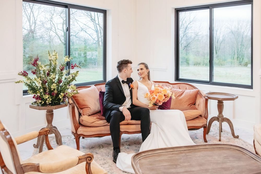 Modern wedding venue interior with large windows, leather chairs and natural lighting.