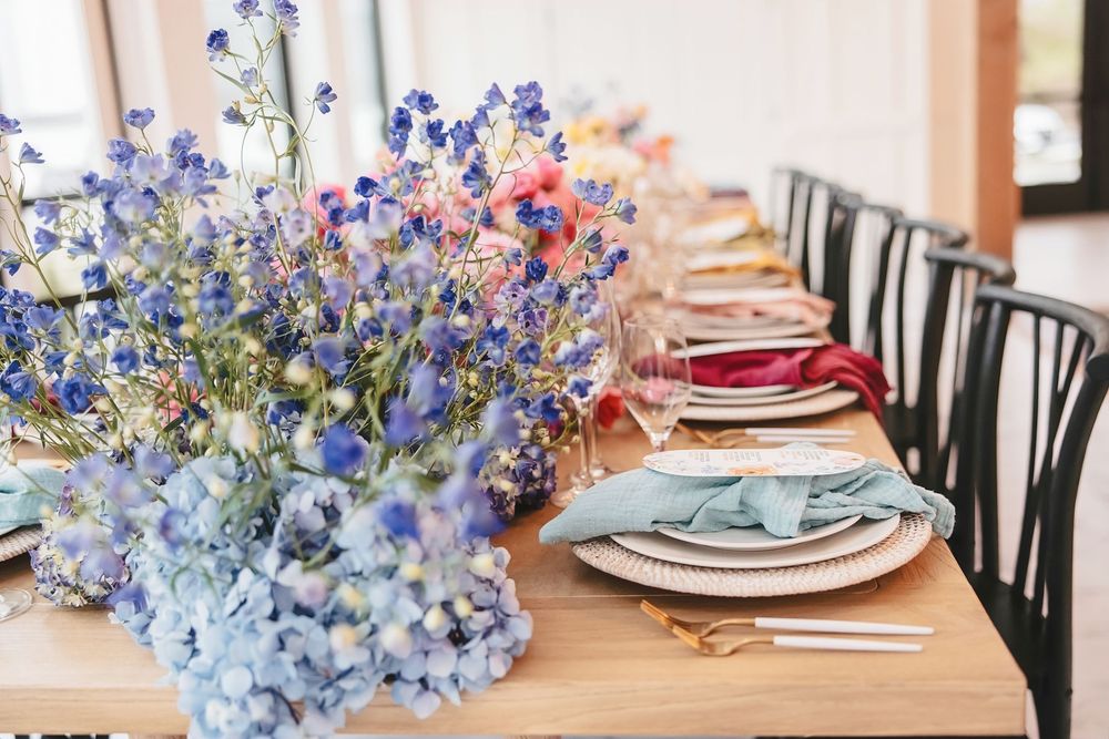 Blue delphinium flowers arranged alongside pink blooms create an elegant table centerpiece display. White Willow Meadows