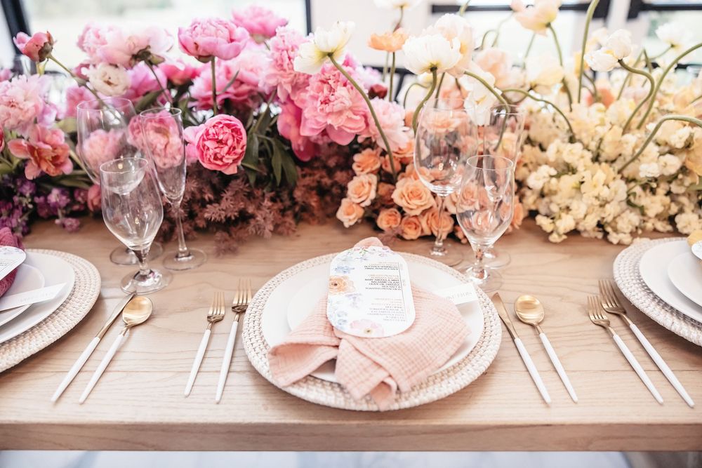 Long banquet table adorned with a lush floral runner featuring pink and peach roses.