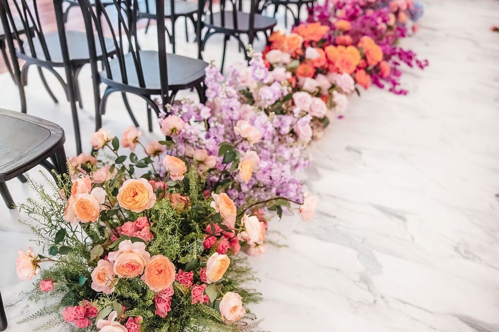 Lush floral arrangement with pink, peach and coral flowers decorating the edge of a paved walkway.