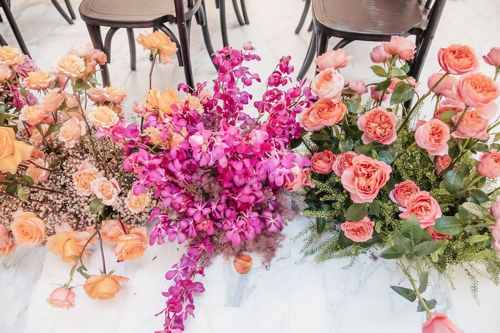 Vibrant wedding floral arrangement with coral peonies and bright pink orchids.