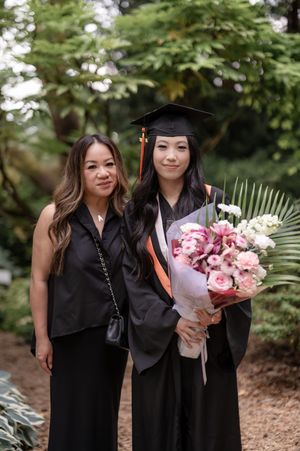 A graduation celebration in a garden with a graduate holding a beautiful pink and white bouquet.