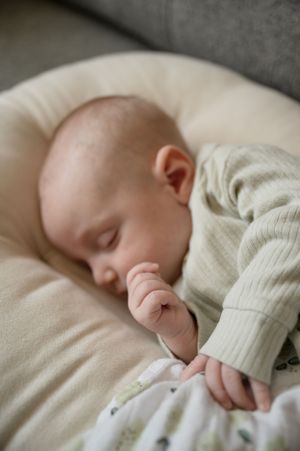 Peaceful sleeping infant in cream sweater on soft cushioning.