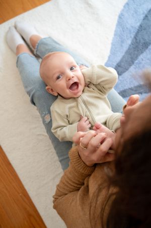 Joyful moment on a blue and white patterned rug with soft natural lighting.