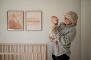 Adult holding baby in cozy nursery setting with minimalist mountain artwork.