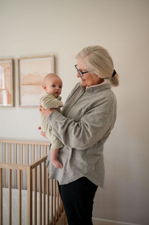 Tender moment by a wooden crib with peaceful natural lighting and pink wall art.