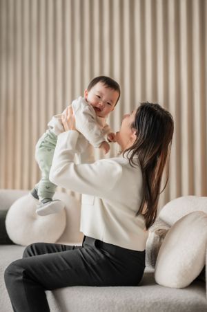 A tender moment shared between parent and baby while sitting on a gray couch with white pillows.