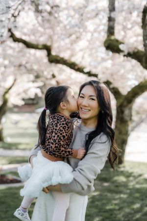 A tender spring moment beneath blooming cherry trees as beautiful blossoms create a dreamy backdrop in the park.