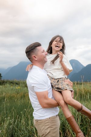 A joyful moment shared between people in a meadow with mountains in the background on a cloudy summer day.