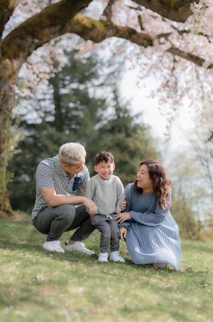 A family shares a joyful moment together under blooming cherry blossom trees on a spring day.